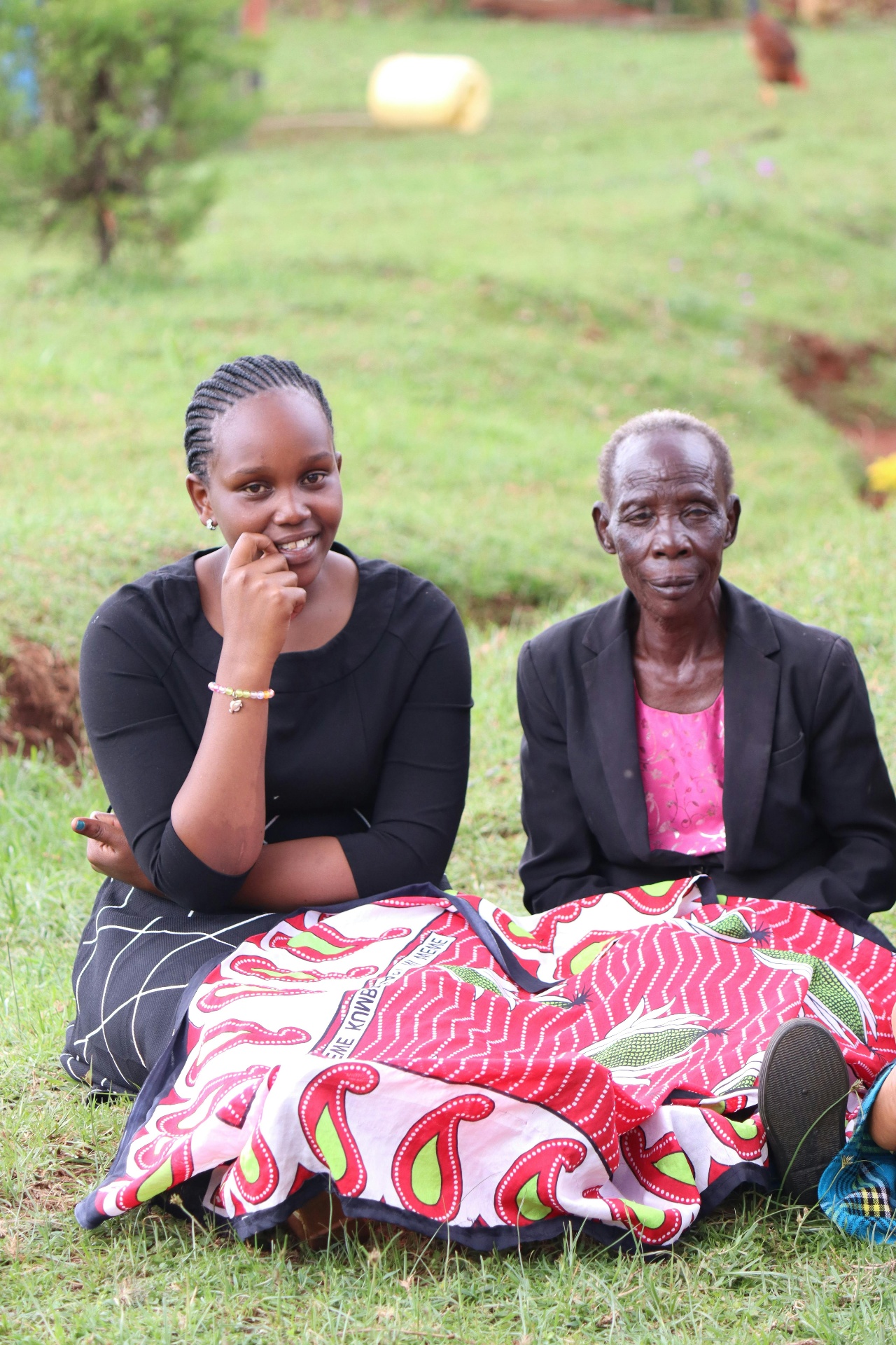 Kenyan daughter sitting beside her elderly mother on the grass